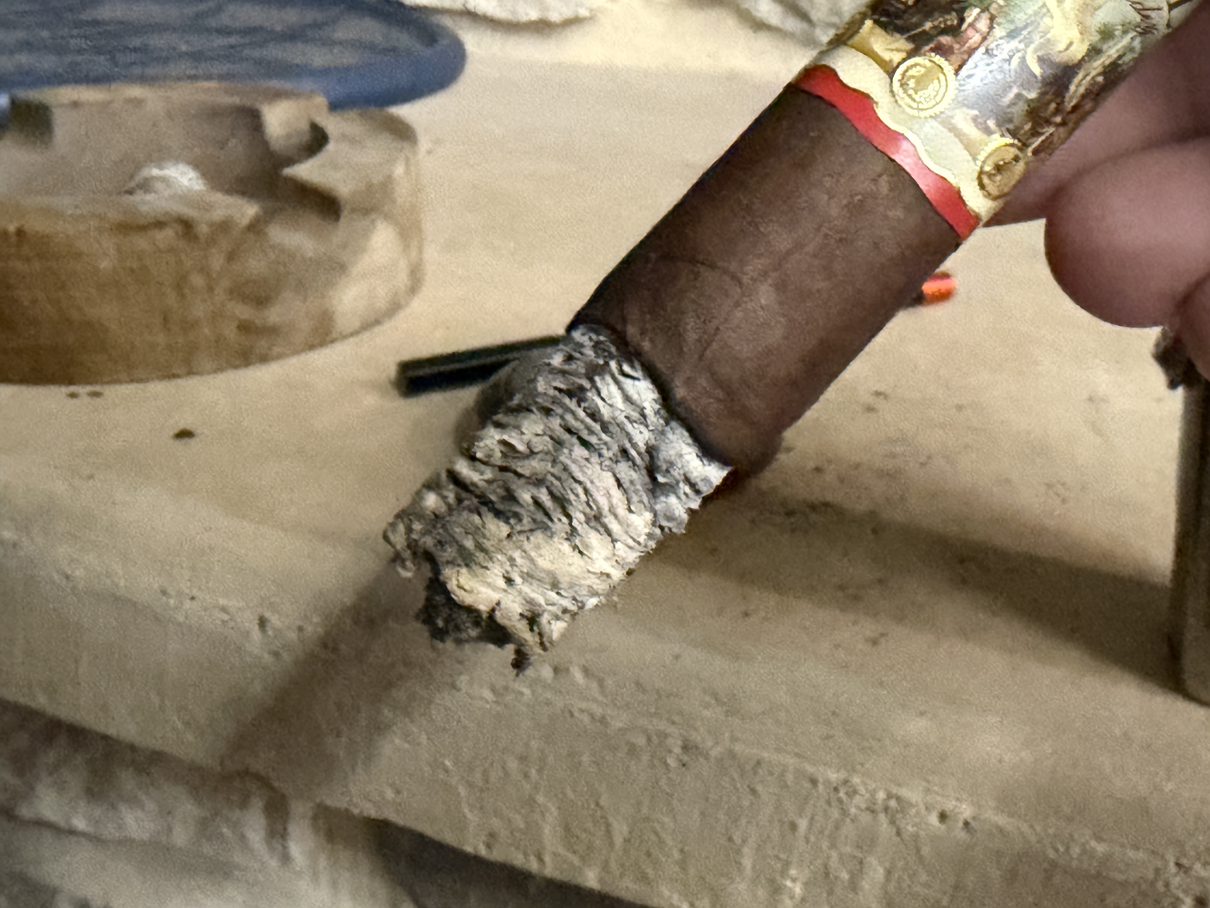 Inch of craggy stacked gray ash on the New World Gobernador Toro, edge of the band visible below