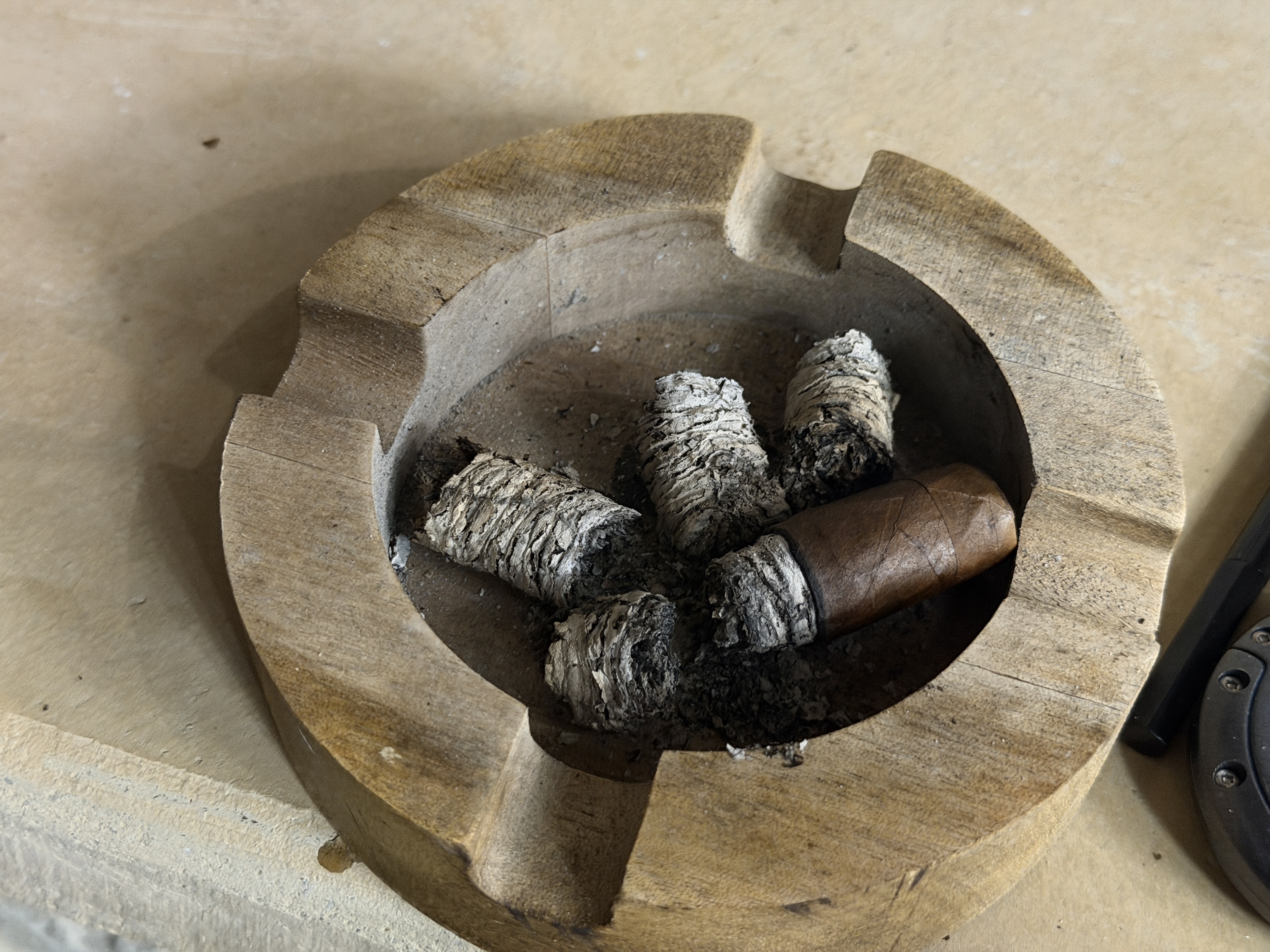 Nub of the New World Gobernador Toro resting in a wooden ashtray surrounded by intact ash stacks