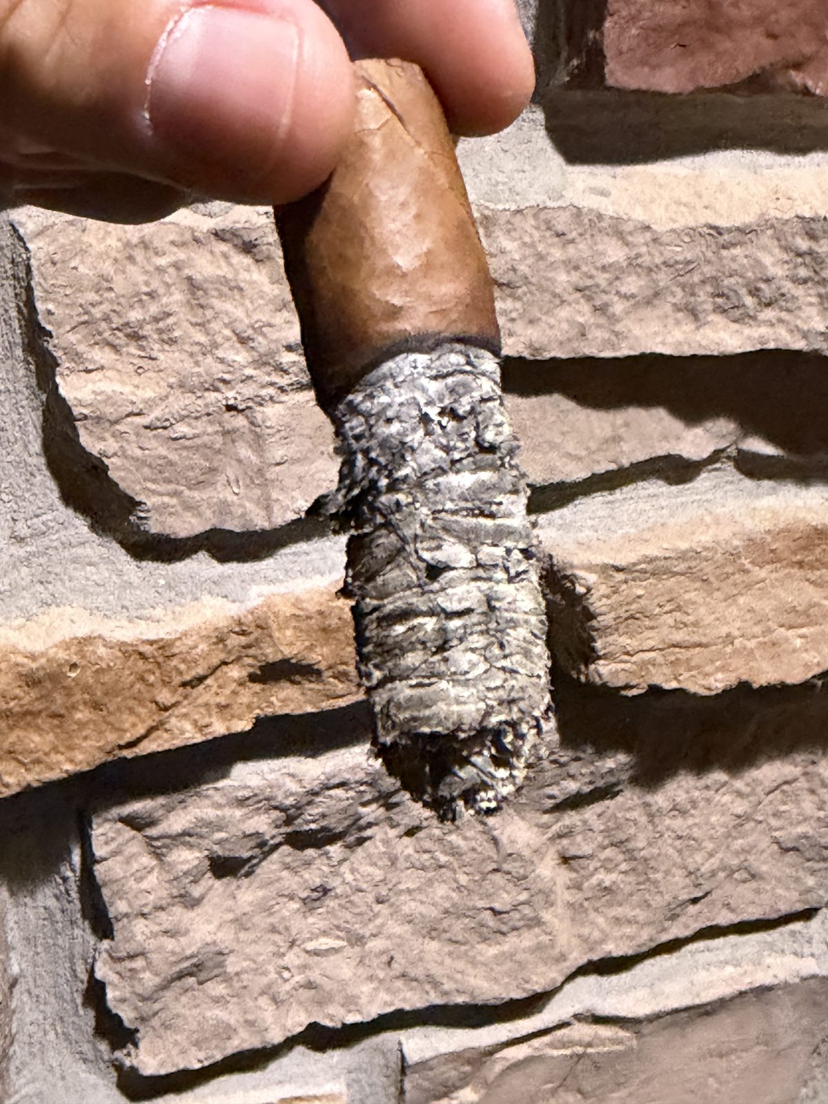 The Asylum 13 Corojo smoked down toward the nub in the final third, tight grey ash on the foot