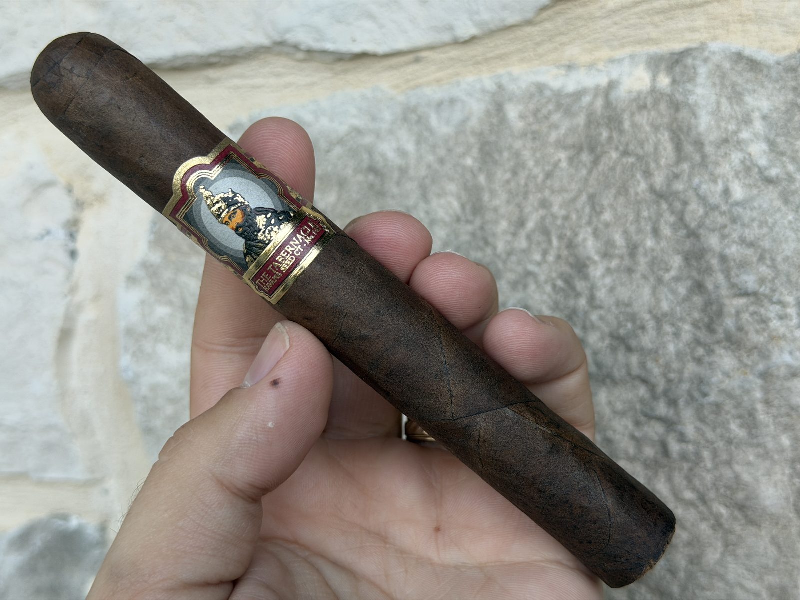 Foundation Tabernacle Havana Seed CT No. 142 Toro held in hand before lighting, dark seamless wrapper with the ornate Tabernacle band