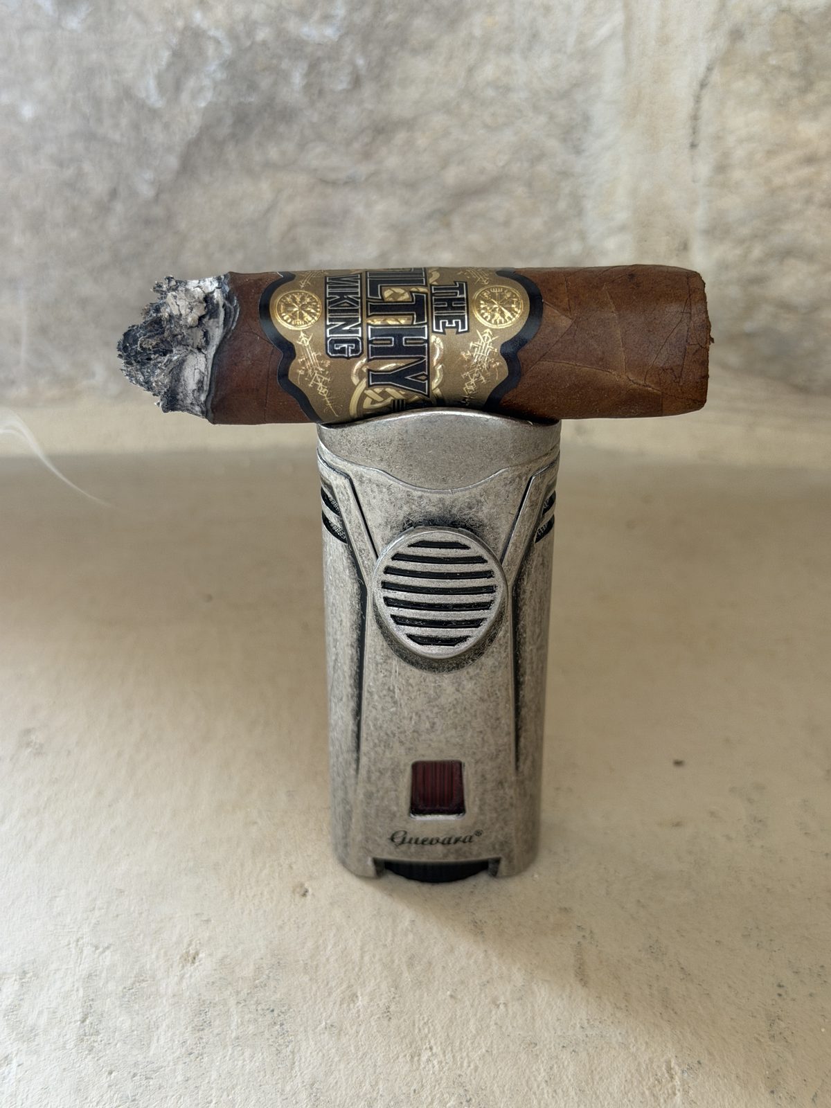 The Filthy Viking Toro resting across the top of the Guevara Lux single-flame lighter, worn silver metal body