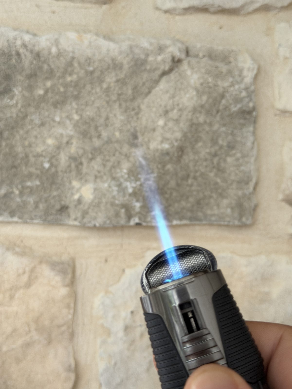 The Jetline Rubanno held in hand outdoors firing a large blue single-jet torch flame at full adjustment