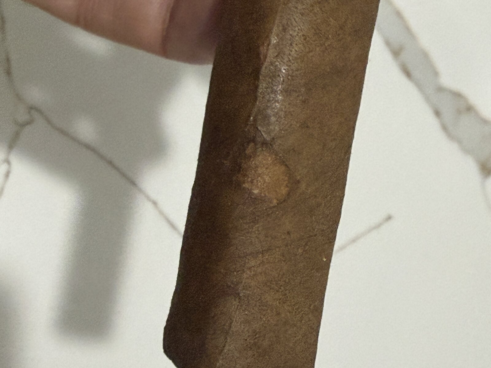 Close-up of the box-pressed body of the Mi Amor showing the pressed facet edges and a small lighter blemish on the medium-brown wrapper