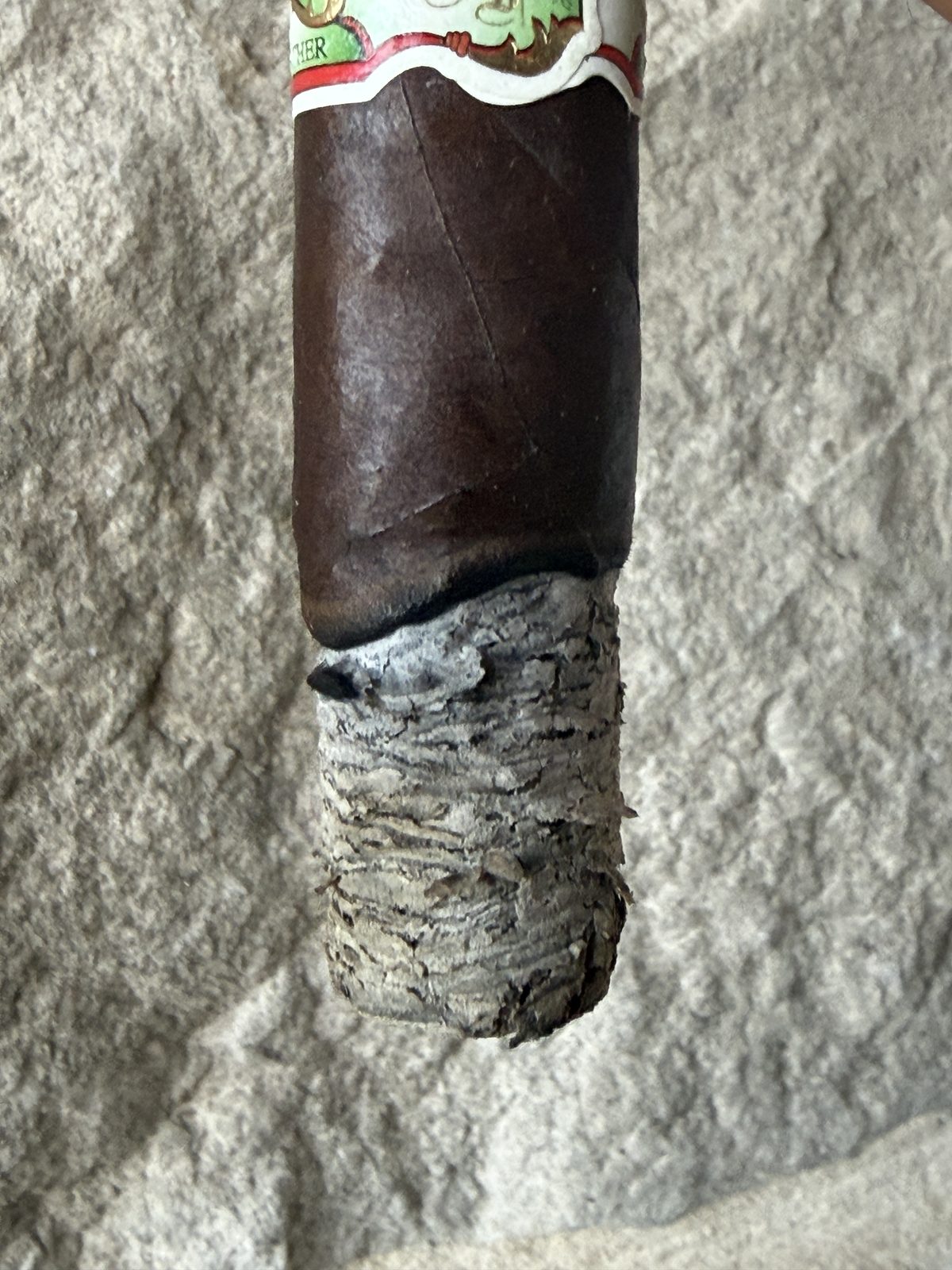 Close-up of the Le Bijou 1922 dark wrapper meeting a pale gray ash, burn line slightly uneven