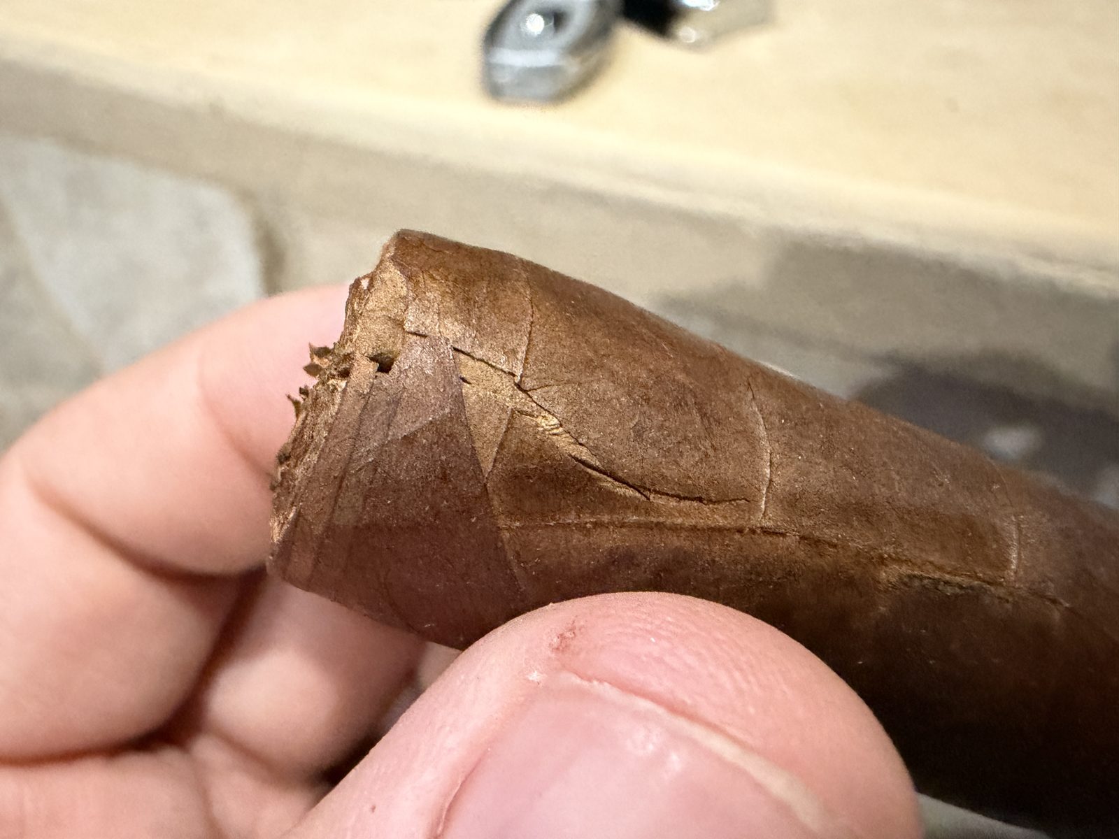 Close-up of the head of the Oliva Serie V Toro with a crack and torn wrapper near the cut cap