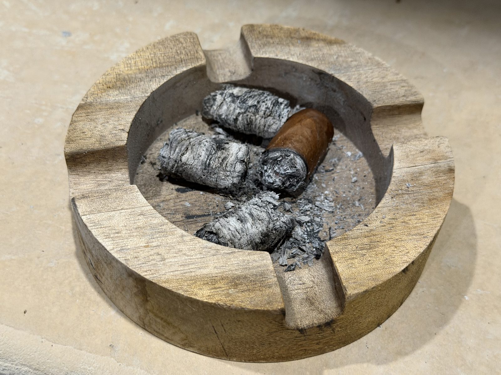 The finished La Historia Silk nub resting in a round wooden ashtray with the night's intact ash chunks around it