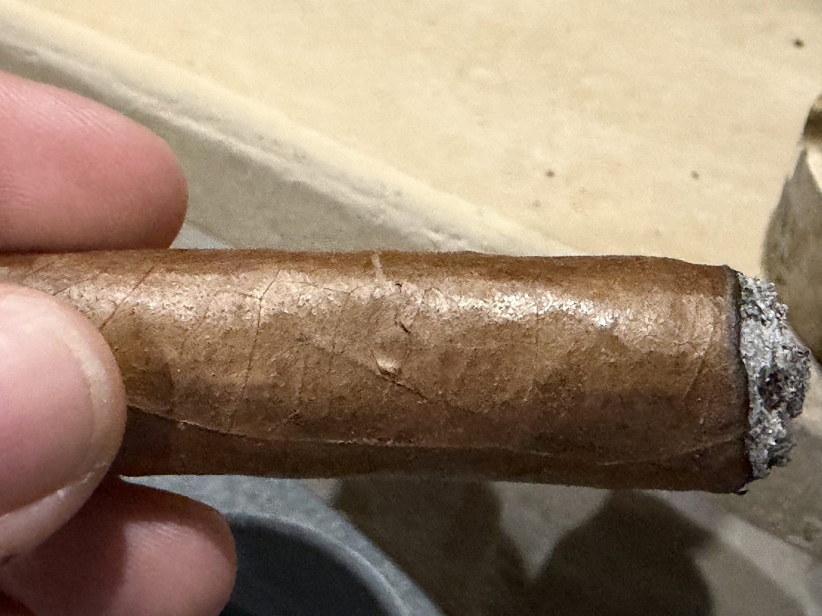Night close-up of the La Historia Silk with the main band removed, showing a crack running around the circumference of the cigar where the band had been