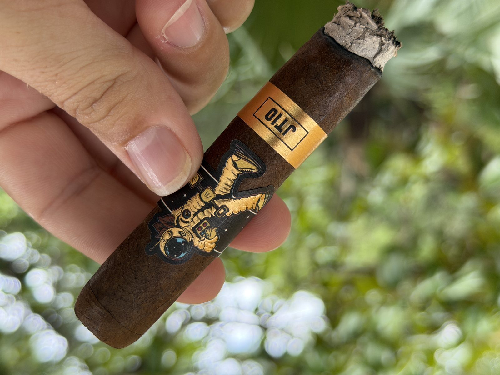JT10 held at an angle showing chunky gray ash above the gold JT10 band